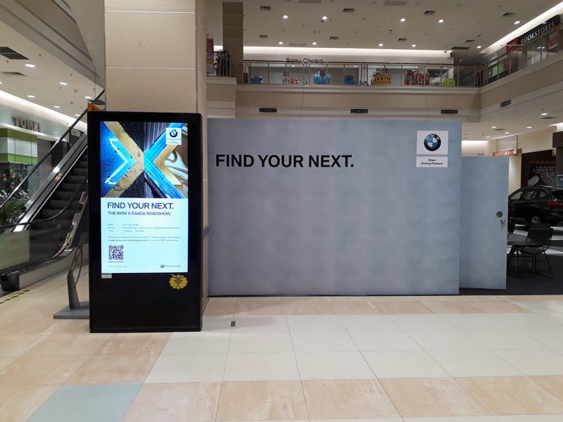 Kesion Malaysia digital standing screen and physical hoarding displaying a BMW X Range roadshow advertisement in Malaysia shopping mall.