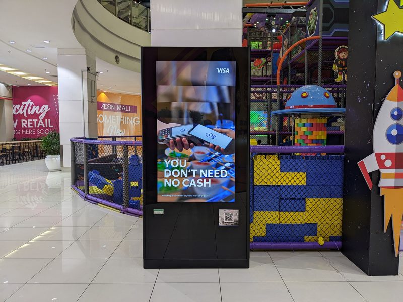 Kesion Malaysia digital standing screen displaying a Visa contactless payment advertisement in a shopping mall.