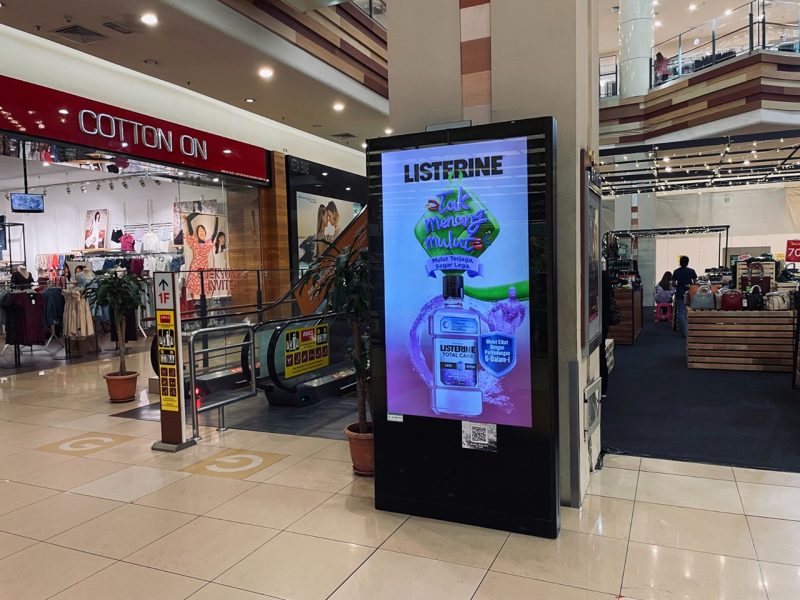 Kesion Malaysia digital standing screen advertising Listerine Total Care mouthwash beside Aeon shopping mall escalator.