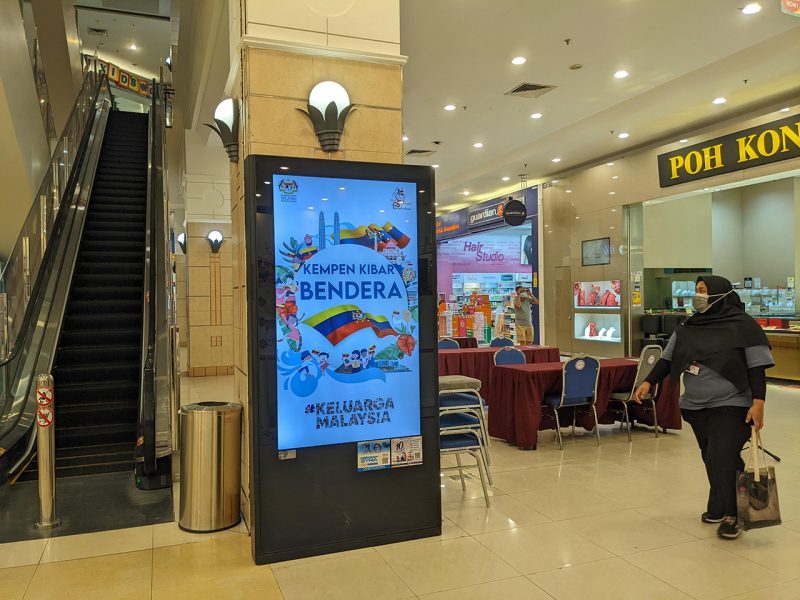 Kesion Malaysia digital standing screen displaying a Kempen Kibar Bendera Keluarga Malaysia public service announcement.