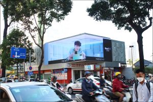 Massive corner digital billboard displaying an OPPO Reno7 Z 5G advertisement above the Youth Employment Service Center at a busy District 1 intersection in Ho Chi Minh City.