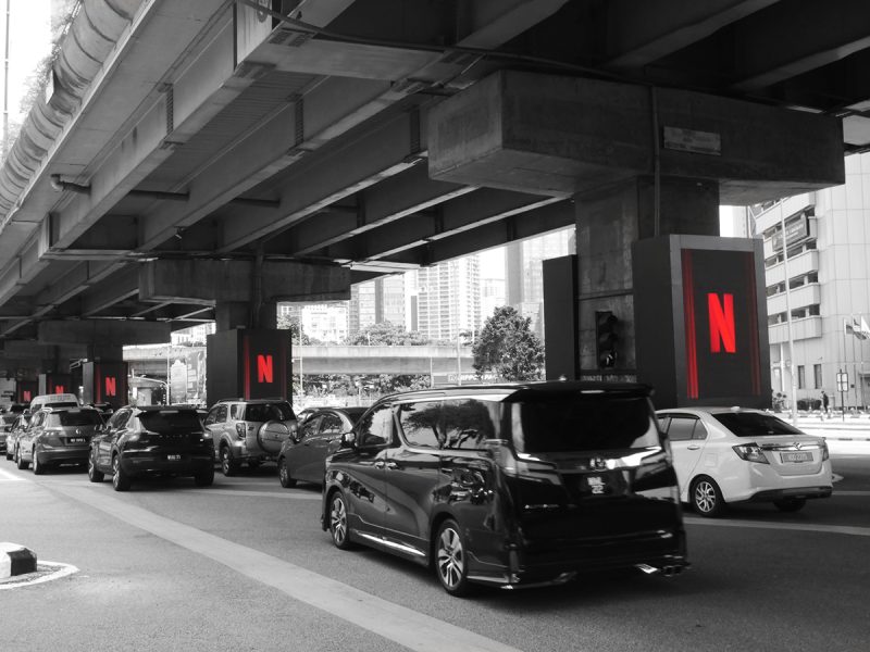 Pillar wrap digital screens displaying the Netflix logo under a highway overpass by Kesion Malaysia