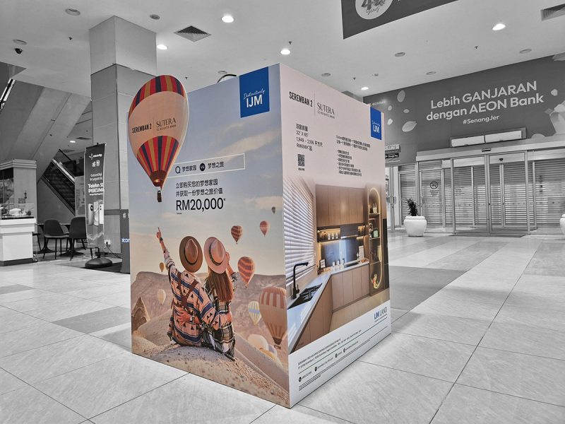 Large IJM Land Seremban 2 Sutera advertising cube in a shopping mall near an AEON Bank branch, showing a hot-air balloon theme and a kitchen interior