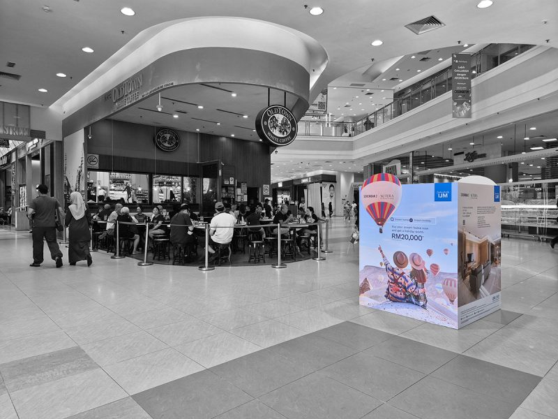Large IJM Seremban 2 Sutera property advertising display in a shopping mall concourse, offering a holiday worth RM20,000 with a home purchase