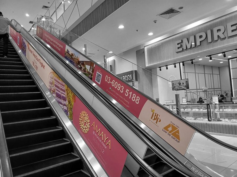 Escalator advertising panels in a shopping mall promoting AMAYA @ Acacia Park Series 2 two-storey terrace homes by BTP and Low Yat Group